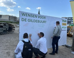 Aanwezigen bij de start bouw van de Gildebuurt schrijven een wens voor de buurt op een spandoek